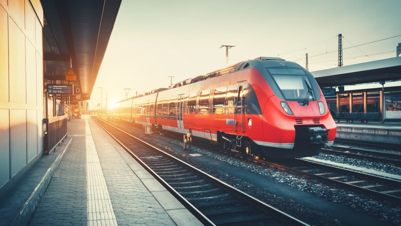 Roter Zug am Bahnhof beim Sonnenuntergang – Deutschlandticket für 63 €/Monat deutschlandweit mit Bus und Bahn reisen