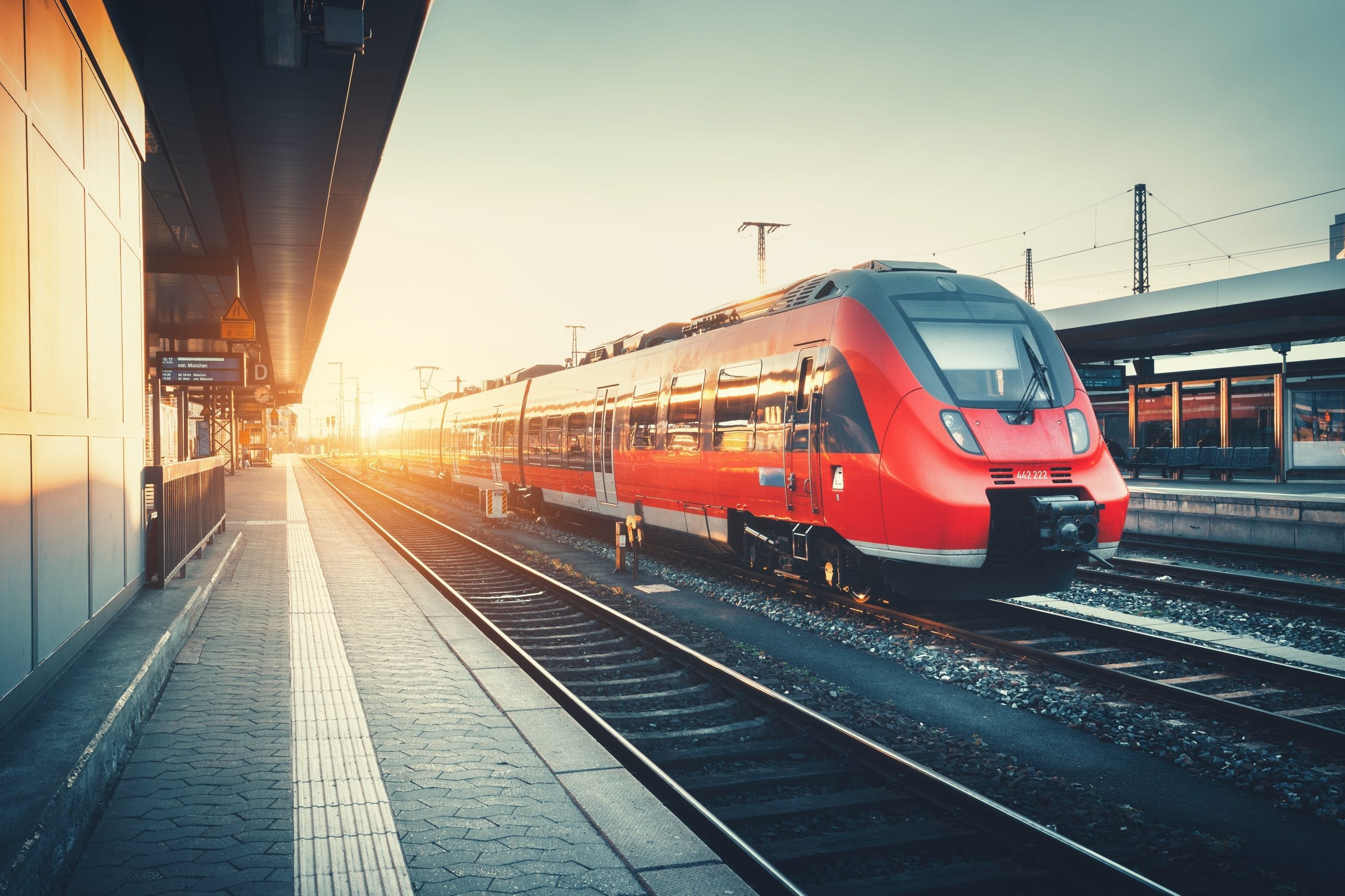 Railway station with beautiful modern red commuter train at sunset